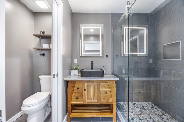 bathroom with a shower with door, vanity, and toilet