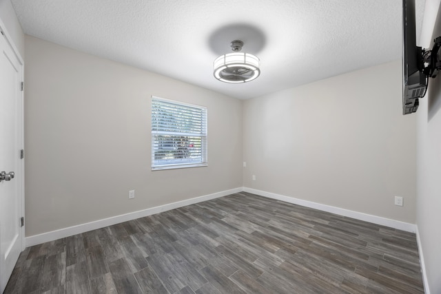 spare room featuring dark hardwood / wood-style floors and a textured ceiling