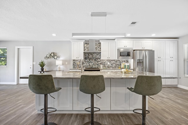 50 Dufferin St, Saint Augustine, FL 32084 - kitchen featuring appliances with stainless steel finishes, wood finished floors, a large island, white cabinets, and a breakfast bar area
