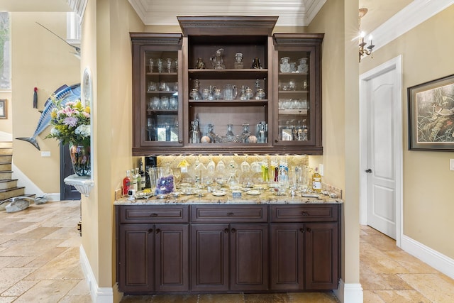 bar featuring light stone countertops, dark brown cabinets, backsplash, and ornamental molding