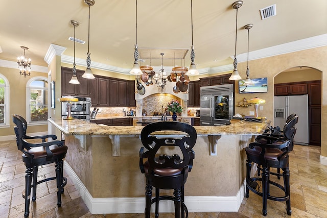 kitchen featuring white refrigerator with ice dispenser, decorative light fixtures, stainless steel built in fridge, and a spacious island