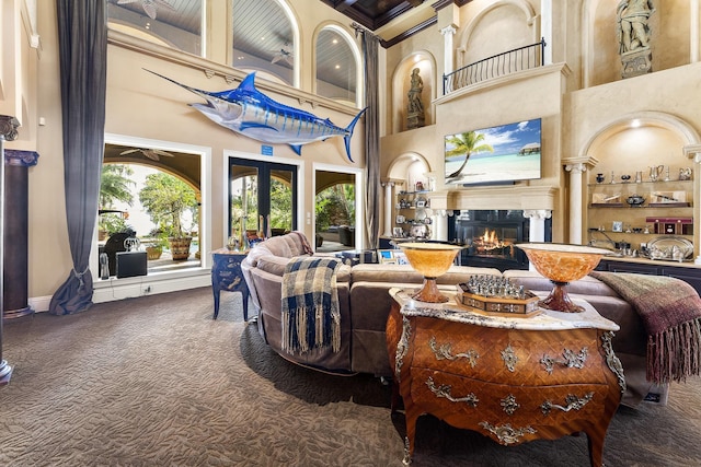 living room featuring french doors, a high end fireplace, dark carpet, and a high ceiling