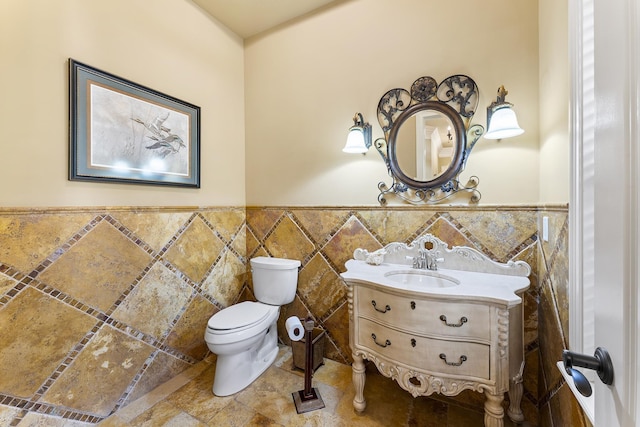 bathroom with vanity, toilet, and tile walls