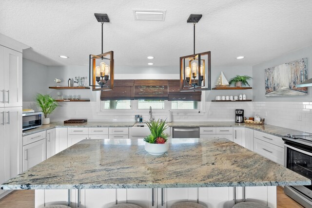 7201 A1A S, Saint Augustine, FL 32080 - kitchen with white cabinetry, open shelves, a kitchen island, visible vents, and stainless steel appliances