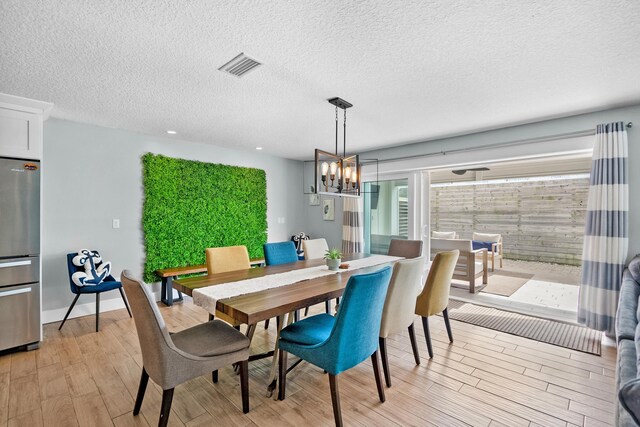 7201 A1A S, Saint Augustine, FL 32080 - dining space featuring visible vents, baseboards, a notable chandelier, a textured ceiling, and light wood finished floors