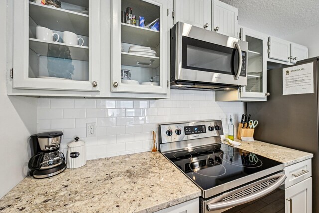 7201 A1A S, Saint Augustine, FL 32080 - kitchen with a textured ceiling, glass insert cabinets, white cabinets, and stainless steel appliances
