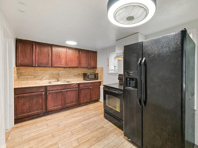 kitchen with backsplash, sink, black appliances, and light wood-type flooring