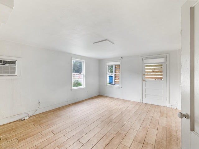 spare room with a wall mounted AC and light hardwood / wood-style flooring