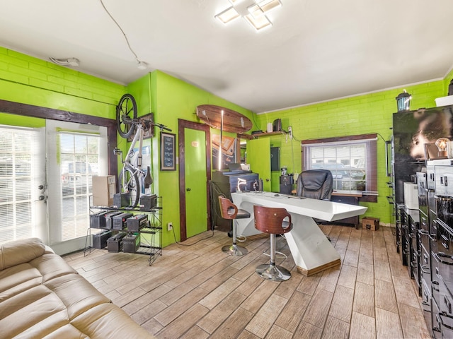 office with light hardwood / wood-style flooring and brick wall