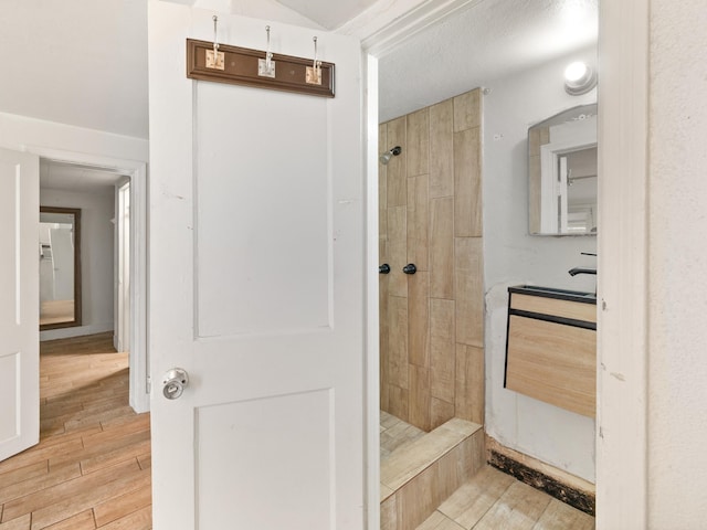 bathroom featuring hardwood / wood-style flooring and a tile shower