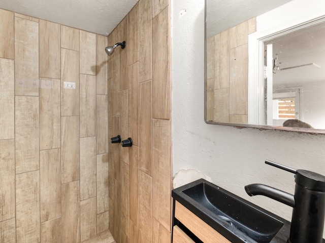 bathroom with vanity, a tile shower, and a textured ceiling