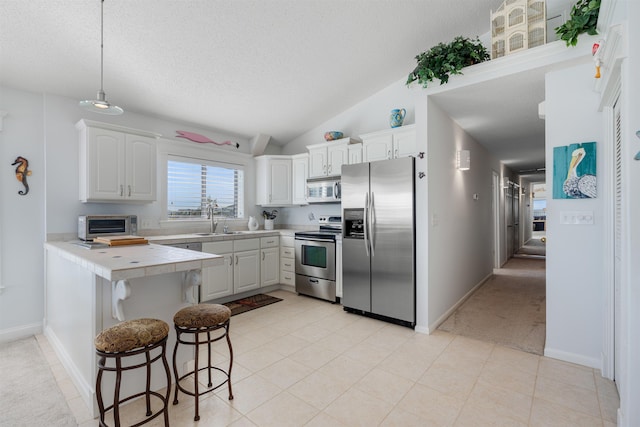 2900 Coastal Hwy, Saint Augustine, FL 32084 - kitchen featuring white cabinets, stainless steel appliances, a peninsula, and a kitchen bar