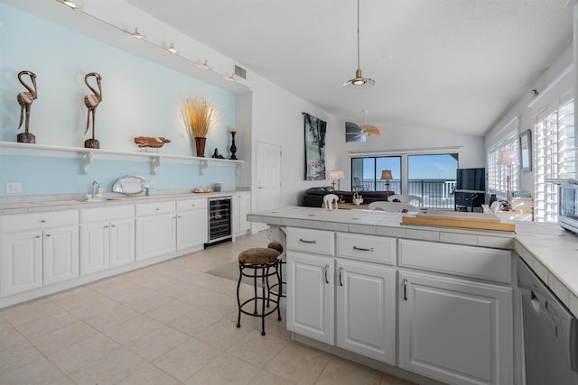 2900 Coastal Hwy, Saint Augustine, FL 32084 - kitchen featuring stainless steel dishwasher, a peninsula, white cabinets, lofted ceiling, and wine cooler