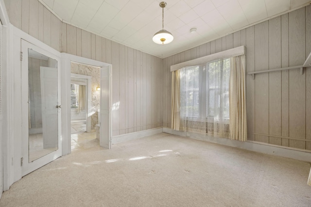 empty room with wood walls and light carpet