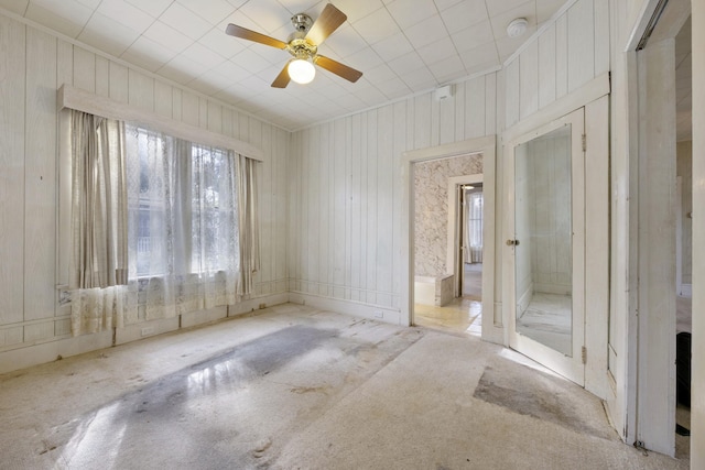 unfurnished room with ceiling fan and wooden walls