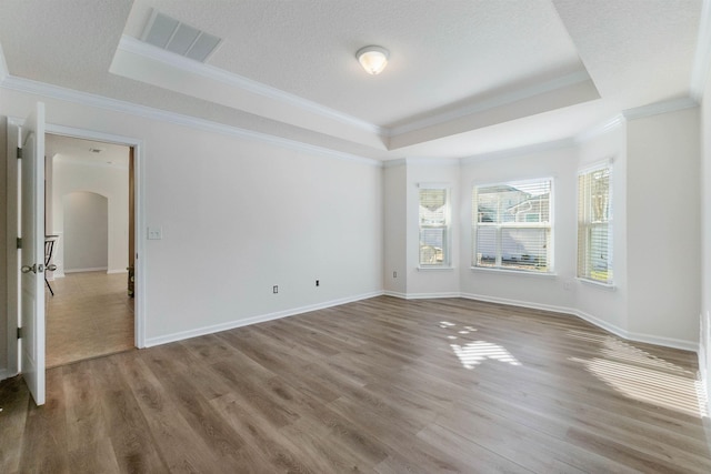 empty room with hardwood / wood-style flooring, crown molding, and a raised ceiling