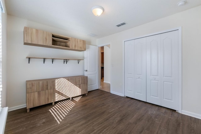 unfurnished bedroom with dark wood-type flooring and a closet