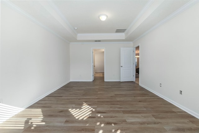 unfurnished bedroom featuring ornamental molding, a tray ceiling, and dark hardwood / wood-style flooring