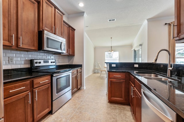 kitchen with pendant lighting, sink, appliances with stainless steel finishes, dark stone countertops, and ornamental molding