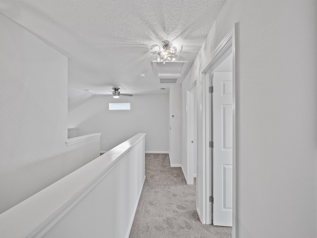 corridor with a textured ceiling, light colored carpet, and lofted ceiling