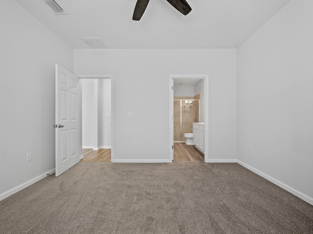 unfurnished bedroom featuring a textured ceiling, ceiling fan, light carpet, and connected bathroom