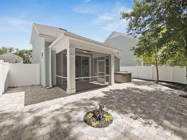 back of house with a hot tub, ceiling fan, a patio area, and a sunroom