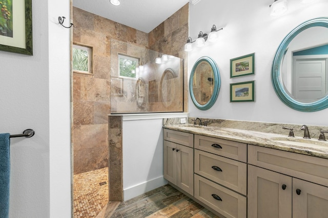 bathroom with tiled shower, vanity, and hardwood / wood-style flooring