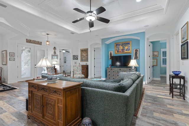 living room featuring ceiling fan, light hardwood / wood-style floors, ornamental molding, and a tray ceiling