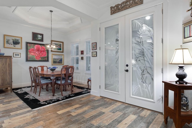 dining space featuring hardwood / wood-style floors, a notable chandelier, ornamental molding, and french doors