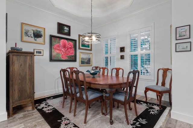 dining space featuring a notable chandelier, light hardwood / wood-style floors, crown molding, and a tray ceiling