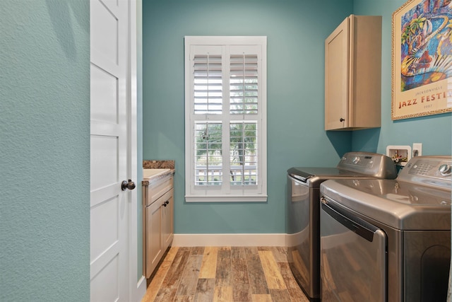 laundry room with cabinets, light hardwood / wood-style flooring, and washer and dryer