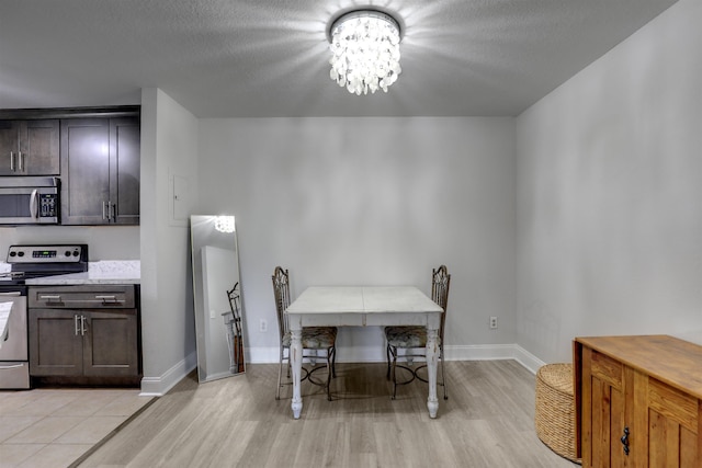 dining area with a textured ceiling, light hardwood / wood-style flooring, and a notable chandelier