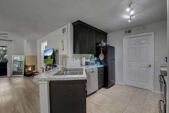 kitchen featuring a tile fireplace, sink, stainless steel appliances, kitchen peninsula, and light hardwood / wood-style floors