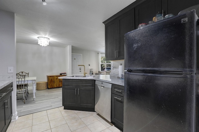 kitchen featuring dishwasher, an inviting chandelier, black fridge, sink, and light tile patterned floors