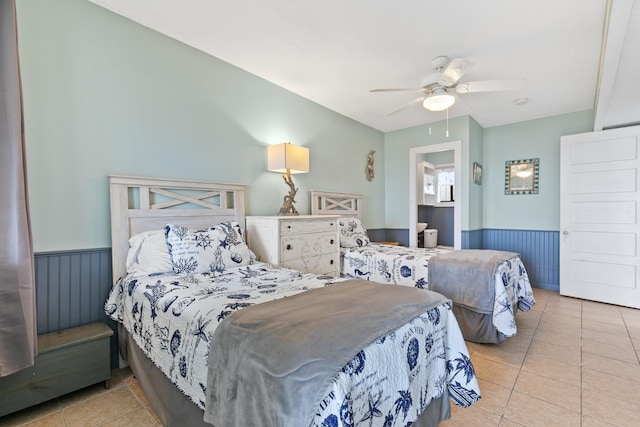 tiled bedroom featuring wainscoting and a ceiling fan