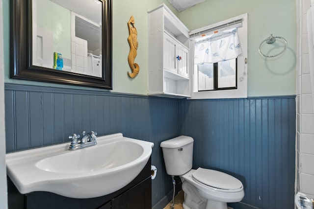 bathroom featuring wainscoting, toilet, and vanity
