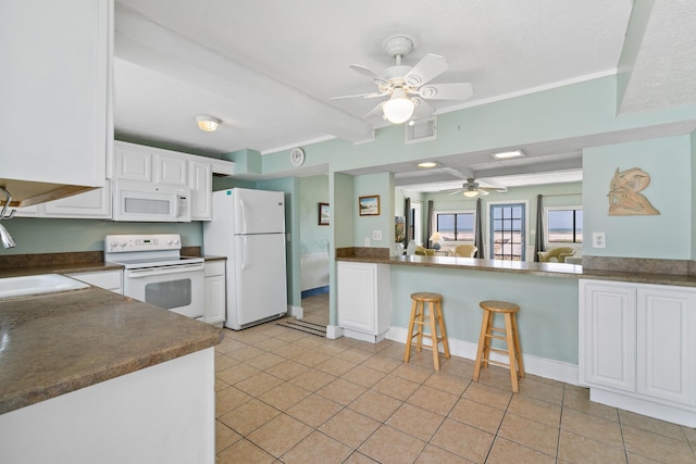 kitchen with dark countertops, a ceiling fan, a sink, light tile patterned flooring, and white appliances