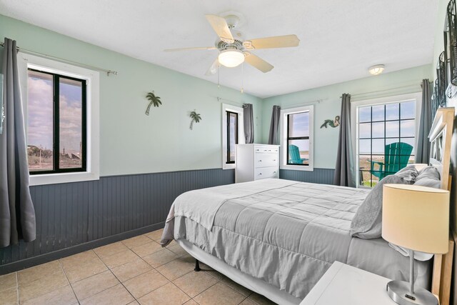 bedroom featuring a wainscoted wall, tile patterned flooring, and ceiling fan