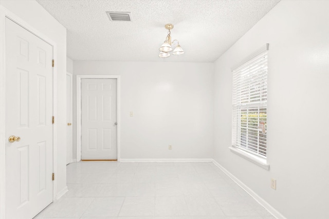 unfurnished room with a textured ceiling and a chandelier