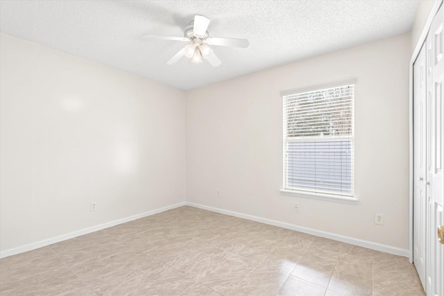 tiled spare room with a textured ceiling and ceiling fan