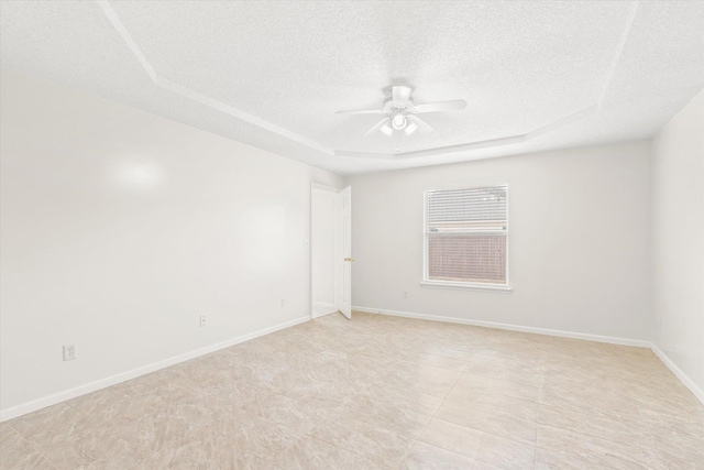 unfurnished room with a raised ceiling, a textured ceiling, and ceiling fan