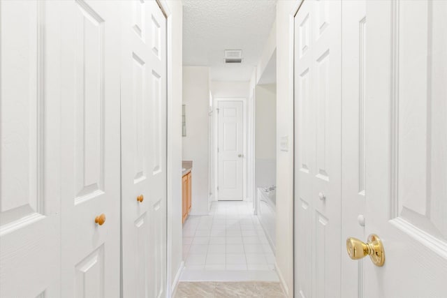 hallway featuring a textured ceiling and light tile patterned flooring