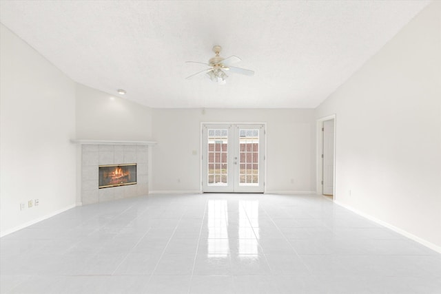 unfurnished living room with french doors, ceiling fan, a fireplace, and light tile patterned flooring