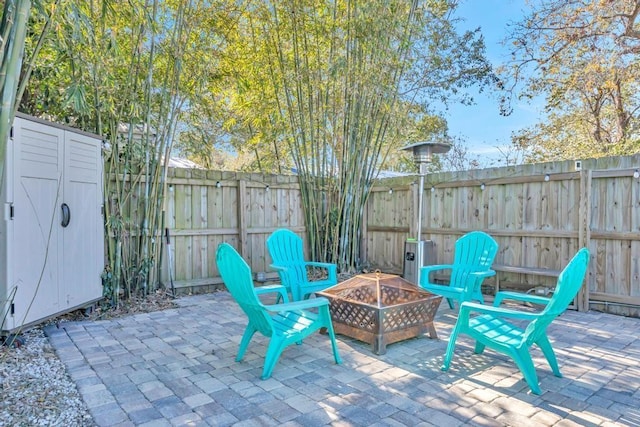 view of patio / terrace with an outbuilding, a shed, an outdoor fire pit, and fence