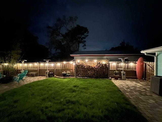 yard at night featuring fence and a patio area