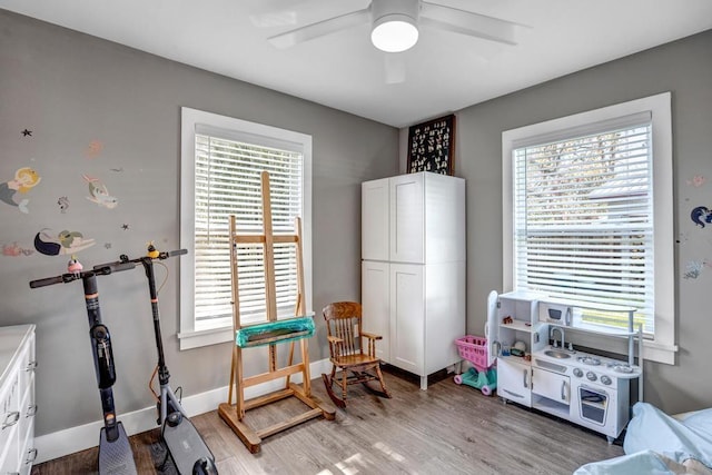 rec room with a wealth of natural light, ceiling fan, baseboards, and light wood-style floors