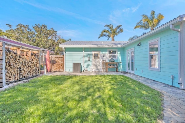 back of house with fence, metal roof, a yard, a patio, and a gate