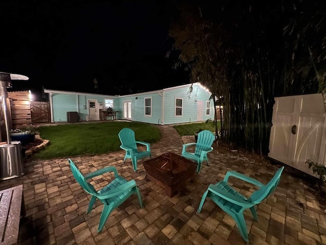 patio at twilight featuring a yard, fence, and a fire pit