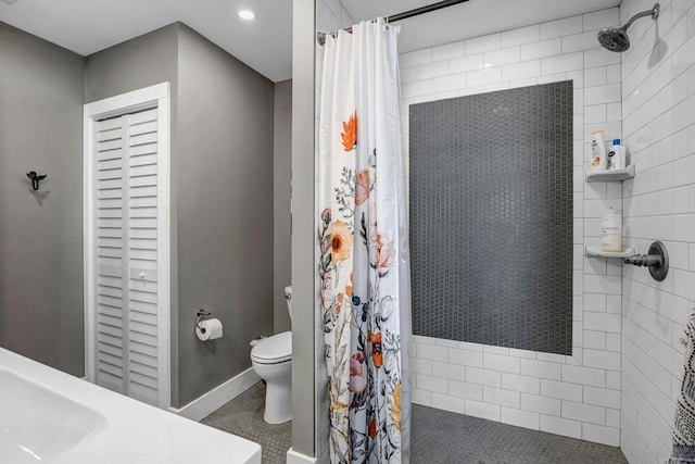 full bath featuring toilet, tiled shower, and baseboards