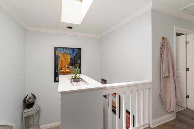 hall featuring a skylight, baseboards, ornamental molding, and wood finished floors